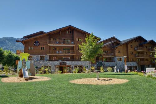 un grand bâtiment avec un parc en face dans l'établissement CGH Résidence Boutique Les Chalets De Laÿssia, à Samoëns