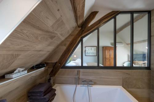 an attic bathroom with a tub and a window at Le Clos du Verger in Levernois