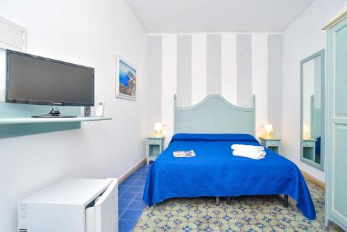 a bedroom with a blue bed and a flat screen tv at Charme Hotel La Villa Tina in Ischia