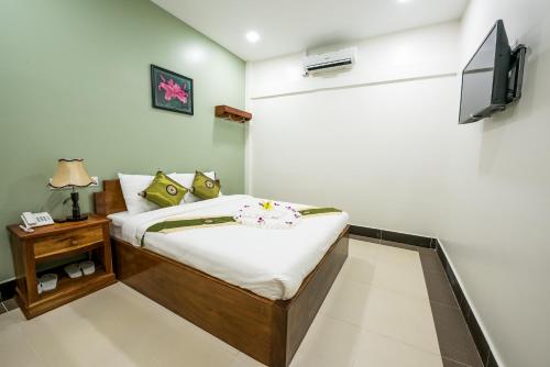 1 dormitorio con 1 cama y TV en la pared en NKS Hotel, en Phnom Penh