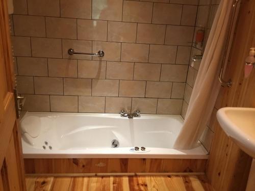 a bath tub in a bathroom next to a sink at Kylemore Pass Hotel in Letterfrack