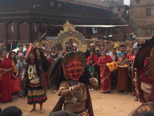 a crowd of people standing around a man wearing a mask at Golden Gate Guest House in Bhaktapur