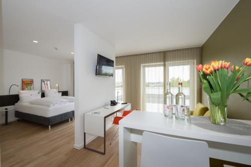 a living room and a bedroom with a table with flowers at K-Apart Hotel & Boardinghouse in Hürth
