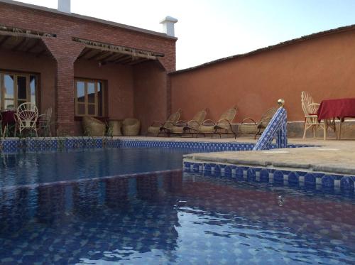 uma piscina em frente a um edifício com cadeiras em Kasbah Petit Nomade em Tinghir