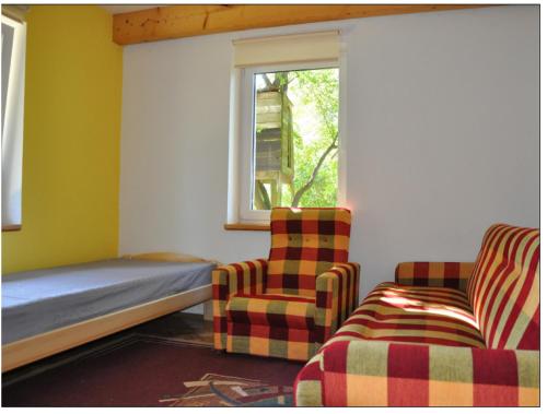 a bedroom with a bed and two chairs and a window at Muzyczna Zagroda in Pietzonken