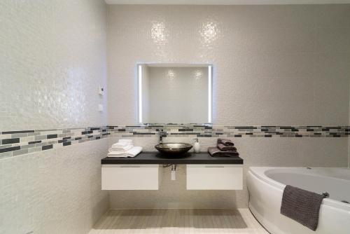 uma casa de banho com um lavatório, uma banheira e um espelho. em Porto de Mos Golf & Beach B&B AL-40312 em Lagos