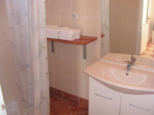 a bathroom with a sink and a shower with towels at Apartmani Mudronja in Murter