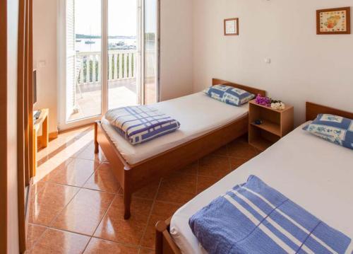 a bedroom with two beds and a balcony at Apartmani Mudronja in Murter