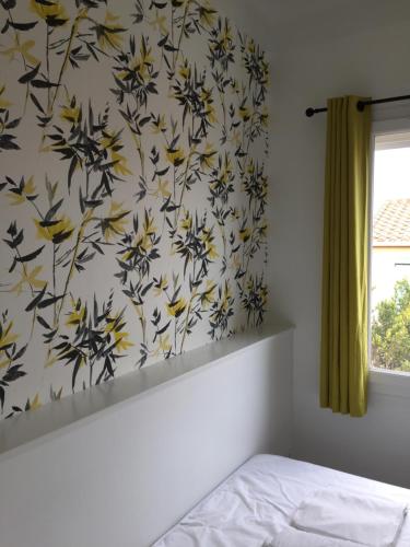 a bedroom with a wall with a flowery wallpaper at Hotel La Casa in Le Barcarès