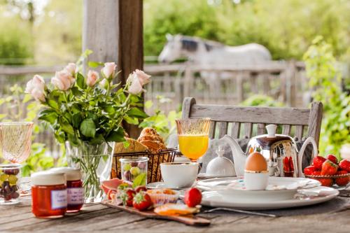 a table with breakfast food and flowers and a horse in the background at B&B De Vossenbarm in Jabbeke