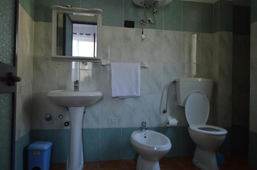 een badkamer met een wastafel, een toilet en een spiegel bij Hotel Bolonja in Shëngjin