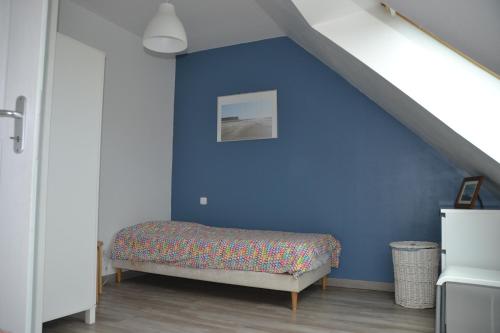 een slaapkamer met een blauwe muur en een bed bij Les Carcahutes in Audresselles