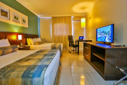 a hotel room with a bed and a flat screen tv at Sun Valley Marília by Atlantica in Marília