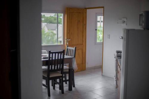 a dining room with a table and chairs and a kitchen at El Faro Apart in Colón