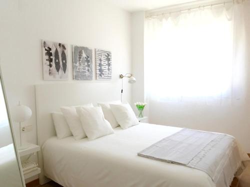 1 dormitorio blanco con 1 cama blanca grande con almohadas blancas en Apartamento EvaHome Roquetas en Roquetas de Mar