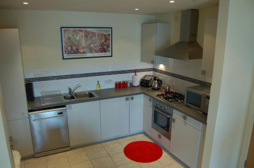 a kitchen with white appliances and a red rug at Apartment 2 The Waterfront in Portaferry
