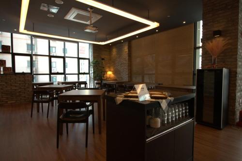 a restaurant with tables and chairs in a room with windows at Vella Suite Hotel in Suwon