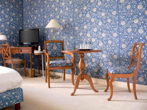 a bedroom with a table and chairs and a tv at Chateau de la Rozelle in Cellettes
