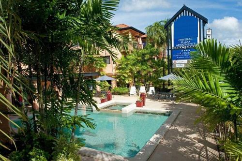 a swimming pool in front of a building with trees at Central Plaza Apartments in Cairns
