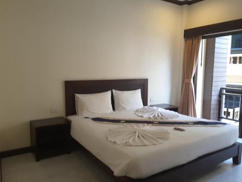a bedroom with a large white bed with a window at Baan Kingkeaw Thamdee Patong in Patong Beach