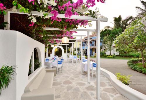 a restaurant with white tables and pink flowers at Radisson Blu Resort, Goa in Cavelossim