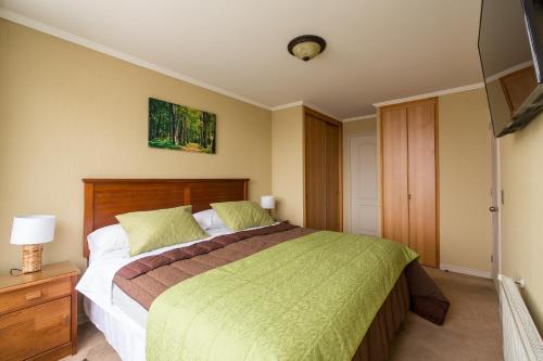 a bedroom with a large bed with a green blanket at EcoApart Concepción in Concepción