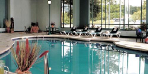a swimming pool in a building with chairs and windows at Wildwood Lodge in Pewaukee