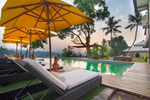 a pool with umbrellas and lounge chairs next to a pool at The Elephant Stables in Kandy
