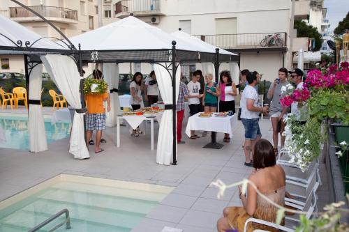 a group of people standing around a tent next to a pool at Ute Hotel in Lido di Jesolo