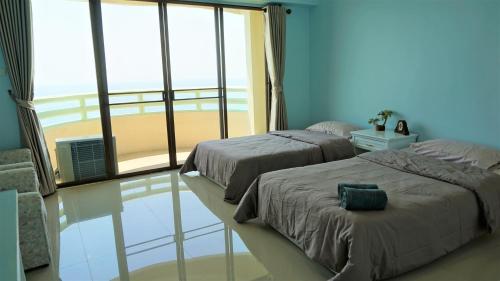 two beds in a bedroom with a view of the beach at VIP Condochain Rayong 410 in Ban Phe