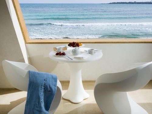 a table and chairs with a view of the ocean at White Bay in Fontane Bianche