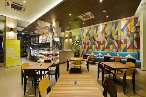 a restaurant with tables and chairs and a colorful wall at POP! Hotel Pasar Baru Jakarta in Jakarta