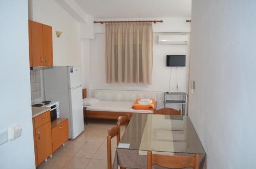 a small kitchen with a table and a refrigerator at Irini Apartments in Keramotí