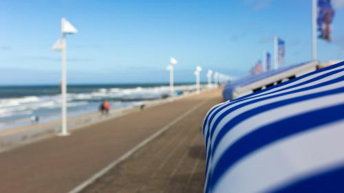 a view of the beach with a blue and white stripe at Michels Thalasso Hotel Nordseehaus in Norderney
