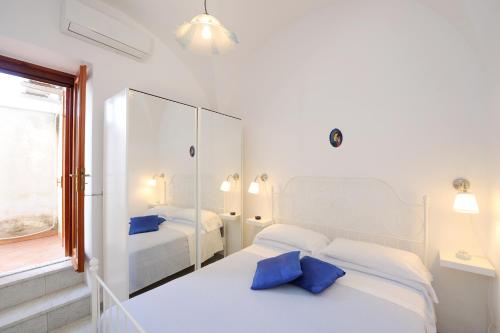 a white bedroom with two beds with blue pillows at L'ancora in Conca dei Marini