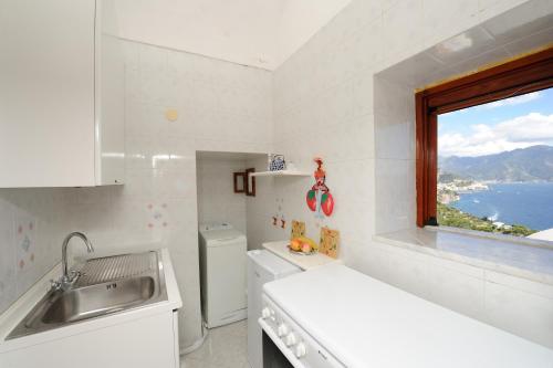 cocina blanca con fregadero y ventana en L'ancora, en Conca dei Marini