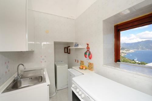 a white kitchen with a sink and a window at L'ancora in Conca dei Marini