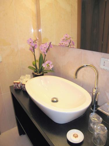 Ein Waschbecken im Badezimmer mit Blumen auf der Ablage. in der Unterkunft Cà Bollani in Venedig
