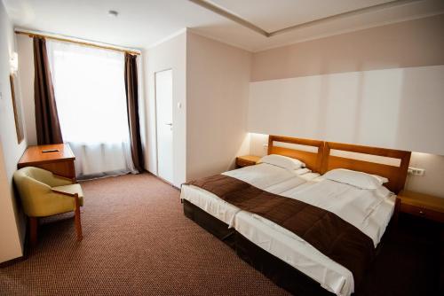 a bedroom with a bed and a chair and a window at Residence Piata Sfatului in Braşov