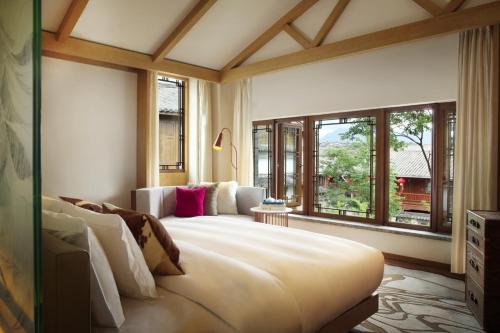 a bedroom with a large bed and large windows at Hotel Indigo Lijiang Ancient Town, an IHG Hotel in Lijiang