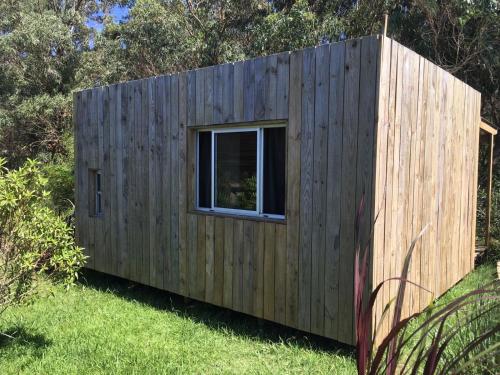 a small wooden house with a window in the grass at Las Luciernagas Posada de Mar in La Pedrera