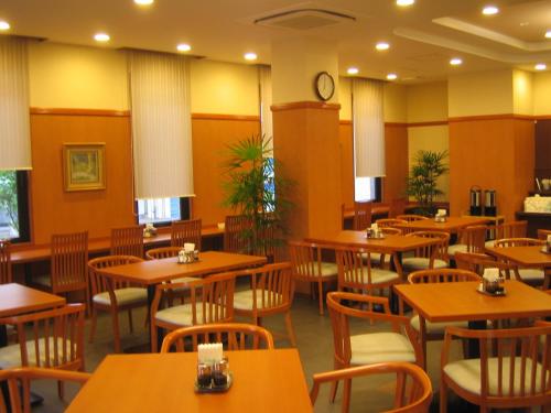 un restaurant avec des tables et des chaises en bois et une horloge dans l'établissement Hotel Route-Inn Kitakyushu-Wakamatsu Ekihigashi, à Kitakyūshū