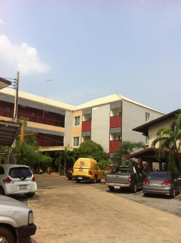 a parking lot with cars parked in front of a building at Pakdee House in Udon Thani