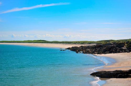 a beach with rocks and the ocean on a sunny day at Cottage 236 Roundstone in Roundstone