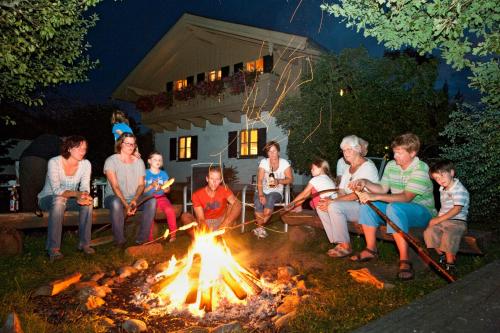 a group of people sitting around a fire at Berghof Heger in Peißenberg