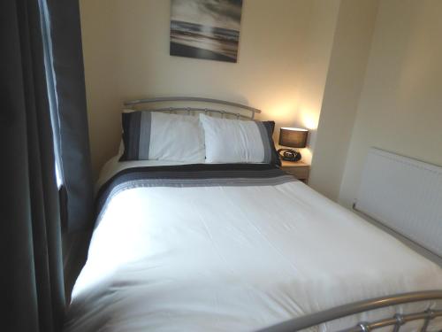 a bedroom with a bed with white sheets at Birdholme House in Chesterfield