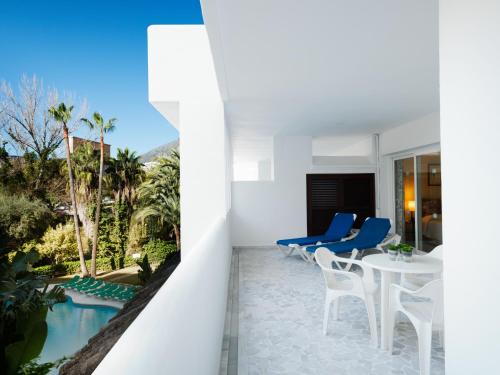 a balcony with a table and chairs and a swimming pool at Aparthotel Monarque Sultán in Marbella