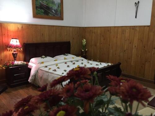 a bedroom with a bed with flowers in the foreground at The Trevene Hotel in Nuwara Eliya