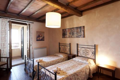 a bedroom with two beds and a chandelier at Residenza Palazzo Saloni in Montalcino