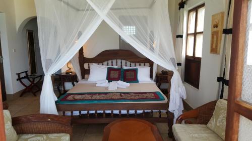een slaapkamer met een hemelbed bij Langi Langi Beach Bungalows in Nungwi